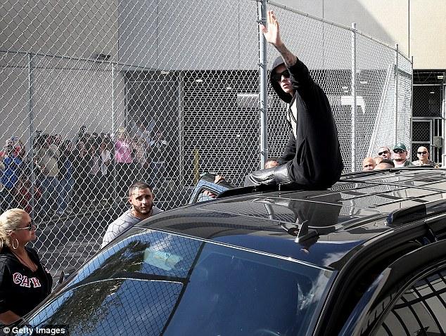 Bieber waves to obsessive fans who were waiting outside of the jail he was at.