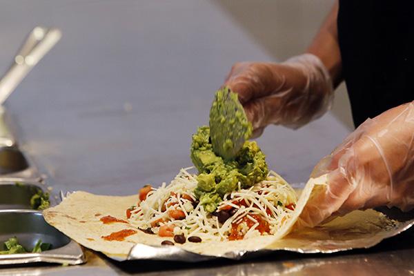 An employee prepares a Chipotle Mexican Grill burrito at the Sunset and Vine store in Hollywood, California, U.S., on Tuesday, July 16, 2013. Chipotle Mexican Grill Inc. is scheduled to release earnings data on July 18. Photographer: Patrick T. Fallon/Bloomberg