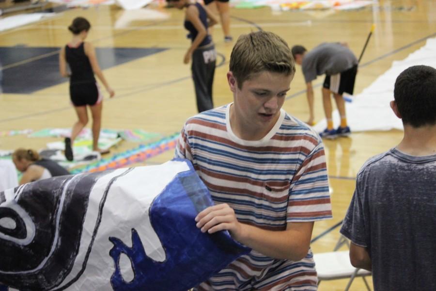 Late on the night before the rally, the ASB members gather all materials and put everything into place. Sophomore Brandon Dubinskas carries a poster up to the wall, looking for the optimal area to hang it.  