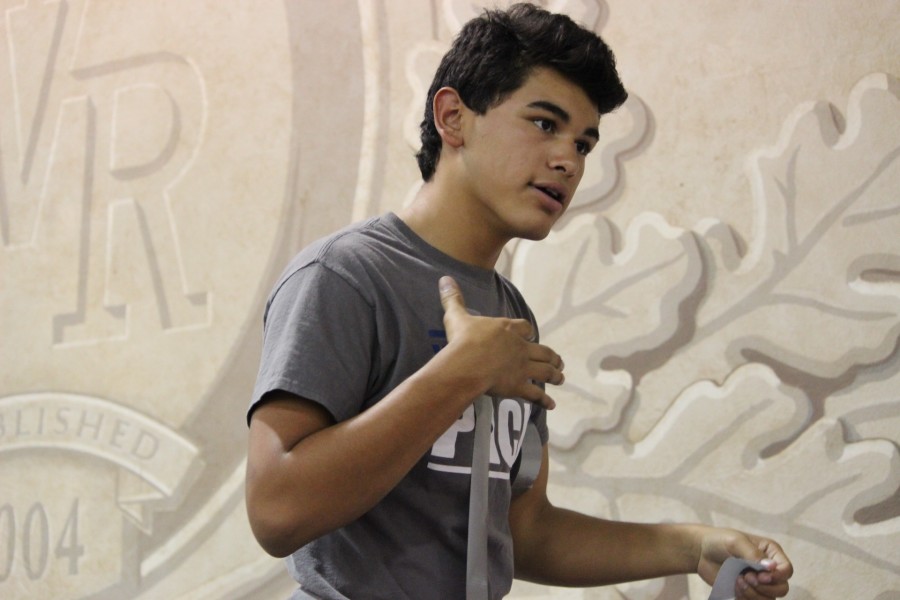 Jessie Garcia, junior member of ASB, coordinates with his teammates while putting duct tape on posters. 
