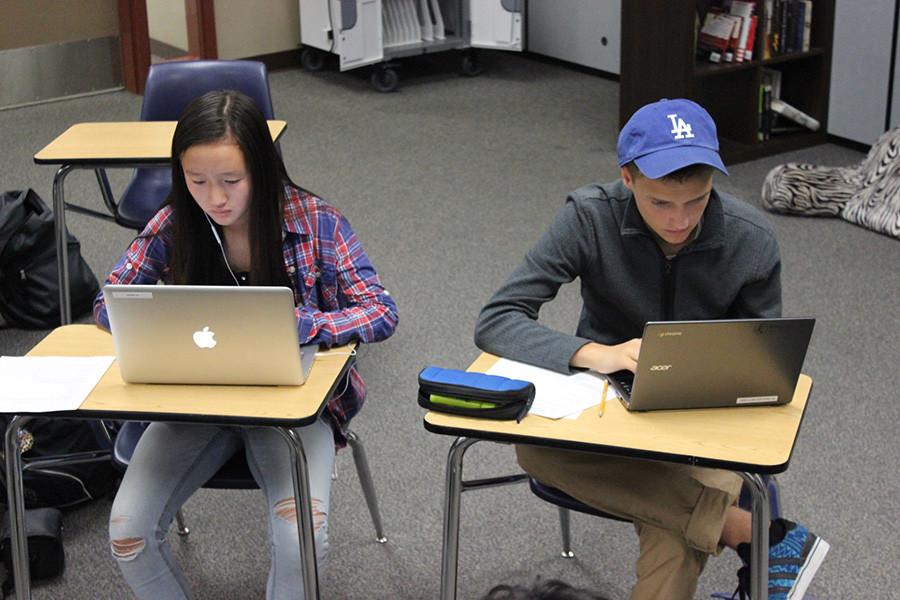 A hat wearing scoundrel distracting his fellow classmate.